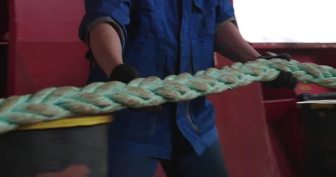 Sailor pulls thick rope along deck arms tense with strength Vídeos de archivo 320436259
