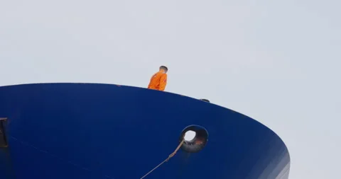 Sailor stands on ship stern focused on mooring ropes 動画素材 320773532