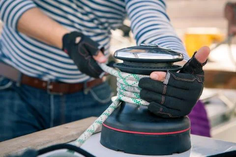 The sailor in the vest pulls the rope on the winch on sailing yacht Stock Photos