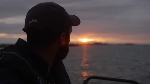 A sailor watches the sunset from his sailboat on the ocean, in Brittany, France Stock Footage 229727133