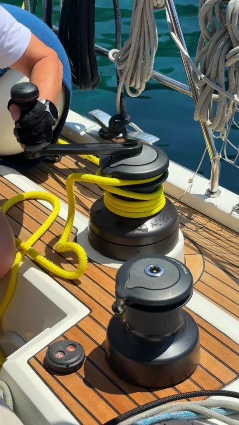 Sailor winding rope around winch on sailing yacht during navigation. Close up of Vidéo 346229259