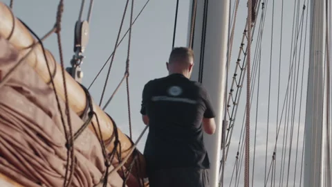 Sailor works on the big expeditional sailing vessel moving in the open ocean Stock Footage 341665439