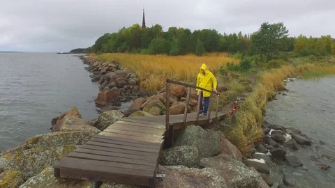 A sailor in a yellow raincoat rises to a stone dock Video stock 89882716