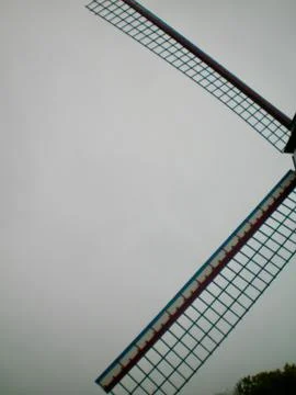 Sails of a wind-mill seen against a grey sky. Stock Photos
