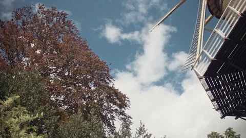 The sails of a windmill fly by from top to bottom in front of a blue sky Stock Footage 85214978