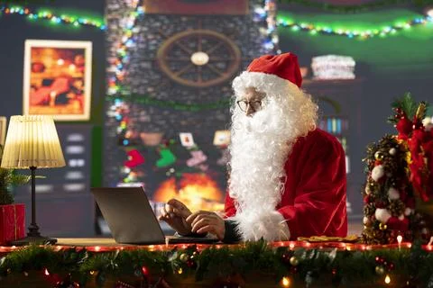 Saint Nicholas is busy online browsing Christmas websites in his festive cabin Stock Photos