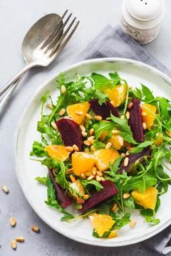 Salad of arugula, baked beetroot, orange and red onions with spices and pine  Stock Photos