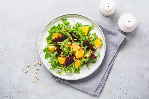 Salad of arugula, baked beetroot, orange and red onions with spices and pine  Stock Photos