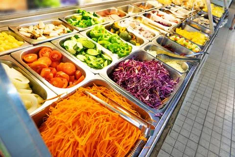 A salad bar with many different types of vegetables, including carrots, broccoli Stock Photos