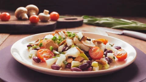 Salad of beans and cherry tomatoes with pineapple and crackers on a beige plate Stock Footage 171681561