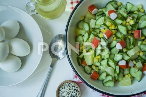 Salad with corn, crab sticks, cucumbers in a white bowl on a white background Stock Photos
