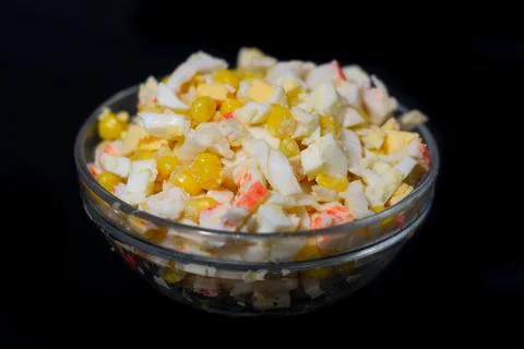 Salad of corn, eggs, cabbage and crab sticks on a black background Stock Photos