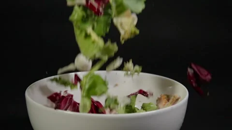 Salad falls onto a plate in slow motion Stock Footage 331879811