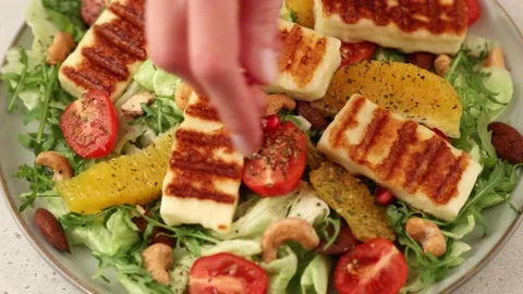 Salad with fried halloumi cheese, nuts, cherry, pomegranate, orange, arugula. Stock Footage 236400794