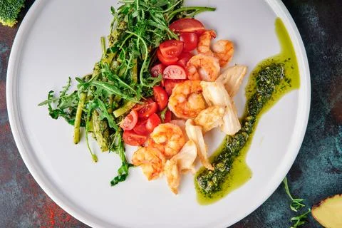 Salad with shrimps, chicken, cherry tomatoes and arugula on white plate on blue Stock Photos