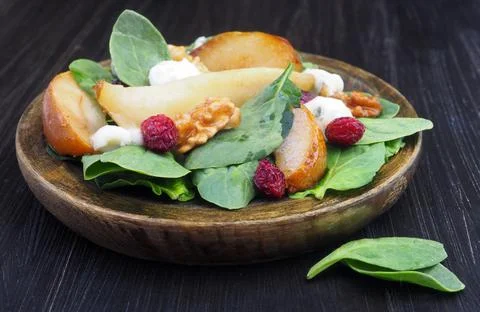Salad of spinach, pears, nuts and blue cheese on a wooden plate 写真素材