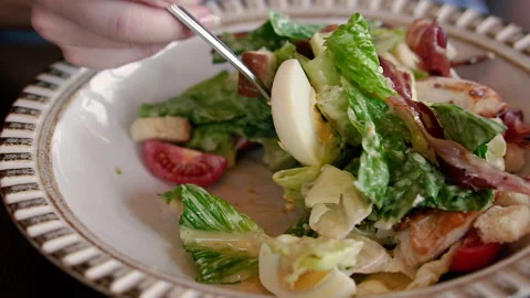 Salad. A woman's hand is stirring a Caesar salad with a fork. Stock Footage 165177438