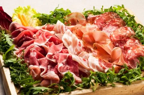 Salami cold cuts in box surrounded with greens Stock Photos