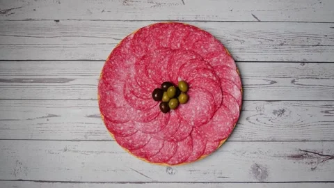 Salami slices, lay down on a plate with olives. Time lapse. Smoked sausage Stock Footage 256809175