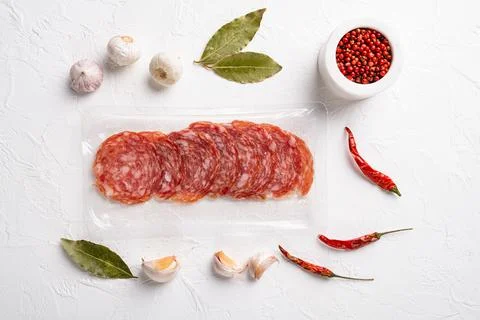 Salami slices vacuum plastic pack, on white stone table background, top view  Stock Photos