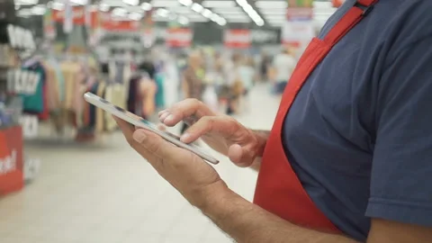 Sales clerk in red apron using a digital tablet with store on background Stock Footage 92238100