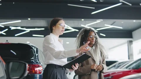 Sales consultant assists a customer in selecting a car at an auto dealership Stock Footage 306323591
