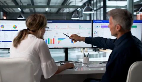 Sales Manager And Assistant Analyze Sales Pipeline Using Multiple Screens. Foto stock