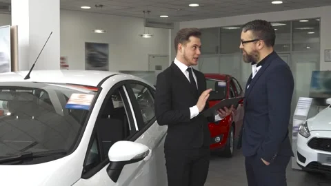 Sales manager explains the contract to the customer at the car dealership Stock Footage 311951242