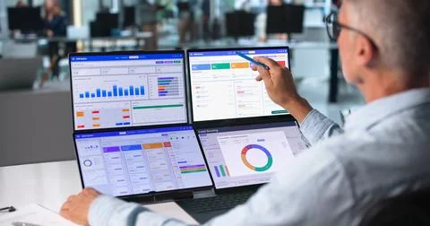 Sales Manager Studies Client Data On Dual Touchscreen Laptops For Growth. Stock Photos