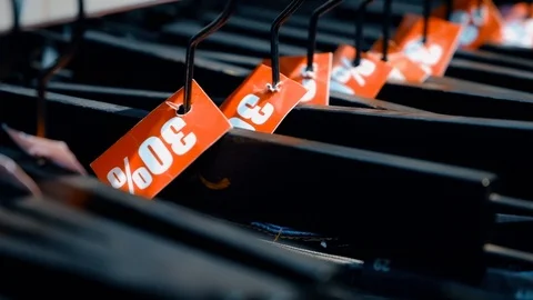 Sales section. Denim items marked with discounts hang on a hanger Stock Footage 116758886