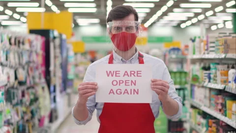 Sales supervisor in red mask and plastic face shield standing in supermarket Stock Footage 148106368