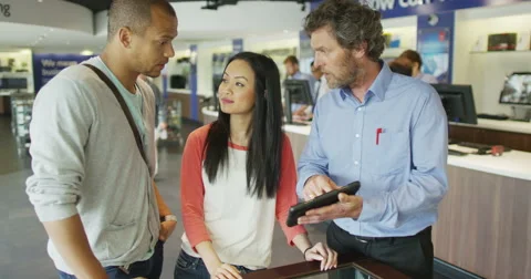 Salesman serving customers in consumer electronics store showroom Stock Footage 67325956