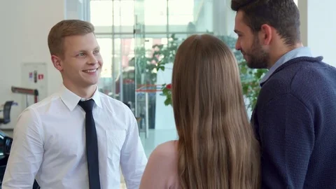 Salesman shakes hands with customer at the car dealership Stock Footage