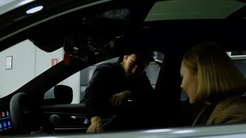 Salesman showing car to client, explaining features indoors Stock Photos