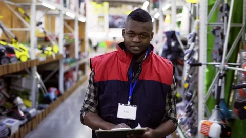 Salesman standing between rows in hardware store, looking to the camera Video stock 171656112