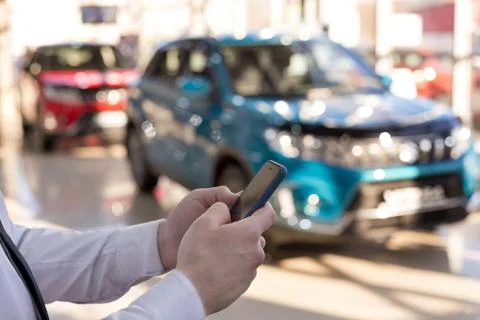 Salesman using mobile smart phone at dealer showroom. Foto stock