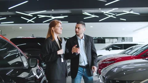 Salesperson explaining car features to potential customer at modern dealership Stock Footage 304714772
