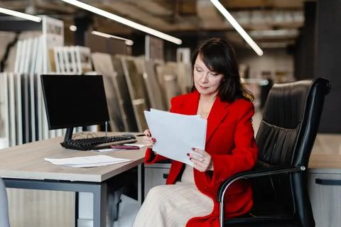 Saleswoman analyzing documents while sitting at desk in furniture store Stock Photos