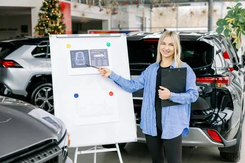 Saleswoman presenting technical data and charts on whiteboard in car dealersh Stock Photos