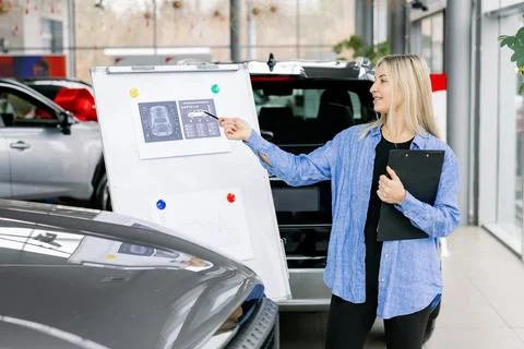 Saleswoman presenting technical data and charts on whiteboard in car dealersh Stock Photos