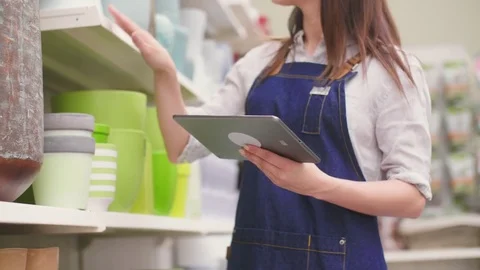 Saleswoman using digital tablet while examining pots in flower shop Stock Footage 79659717