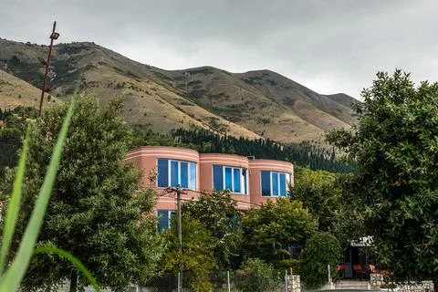 Salmon colored villa with blue windows in Shiroka mountainside greenery Stock Photos