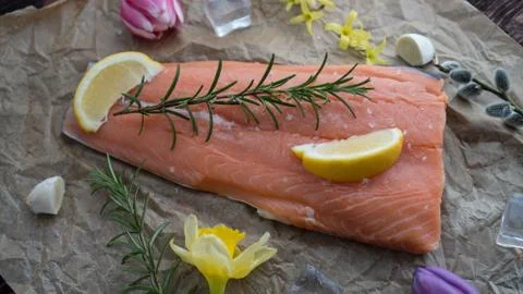 Salmon for the festive Easter table with rosemary and lemon on crumpled paper. Stock Photos