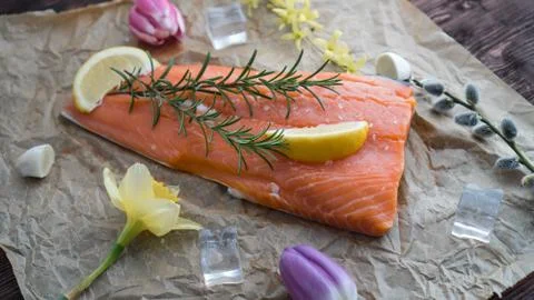 Salmon for the festive Easter table with rosemary and lemon on crumpled paper. Stock Photos