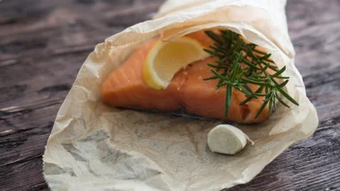 Salmon for the festive Easter table with rosemary and lemon on crumpled paper. Stock Photos