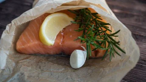Salmon for the festive Easter table with rosemary and lemon on crumpled paper. Stock Photos