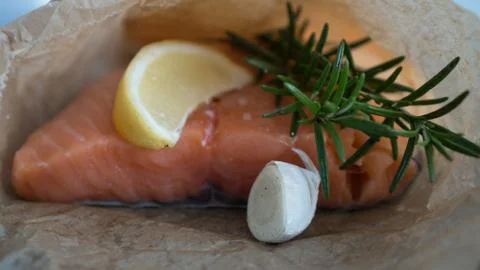 Salmon for the festive Easter table with rosemary and lemon on crumpled paper. Stock Photos