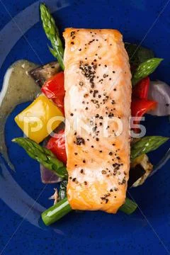 A Salmon Fillet On A Bed Of Asparagus And Peppers