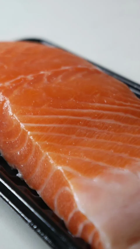 Salmon fillet portion on black plastic supermarket tray 動画素材 330319836