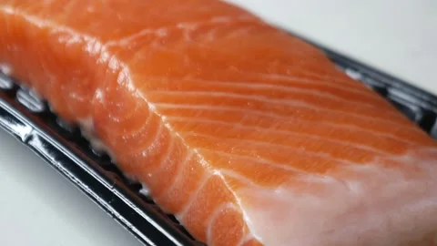 Salmon fillet portion on black plastic supermarket tray 動画素材 330319847